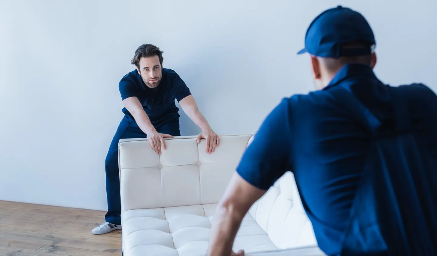 Umzugshelfer von King Umzug tragen ein weißes Sofa beim Umzug